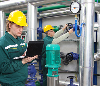 Industrial technicians working on chemical plant piping and pressure valves